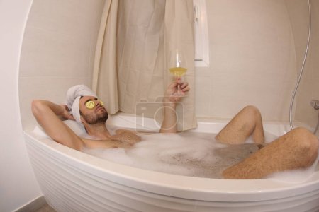 Téléchargez les photos : Wide angle shot of handsome young man with glass of champagne in bath - en image libre de droit