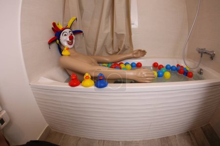 Téléchargez les photos : Plan grand angle de mannequin avec masque de clown et tête dans la baignoire - en image libre de droit