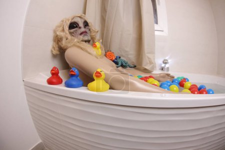 Téléchargez les photos : Wide angle shot of mannequin with alien mask in bath tub - en image libre de droit
