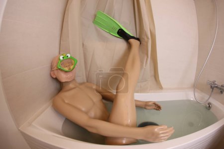 Téléchargez les photos : Wide angle shot of mannequin with snorkeling mask and flippers in bath tub - en image libre de droit