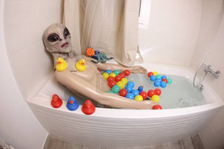 Téléchargez les photos : Wide angle shot of mannequin with alien mask in bath tub - en image libre de droit