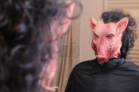 Téléchargez les photos : Close-up shot of person in scary pig mmask in front of mirror at home - en image libre de droit