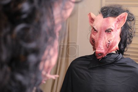 Téléchargez les photos : Close-up shot of person in scary pig mmask in front of mirror at home - en image libre de droit