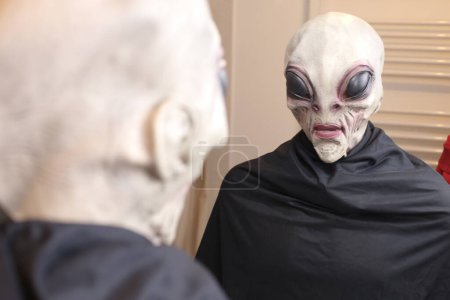 Photo for Close-up shot of person in alien mask in front of mirror at home - Royalty Free Image