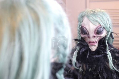 Téléchargez les photos : Gros plan de la personne en masque extraterrestre devant le miroir à la maison - en image libre de droit