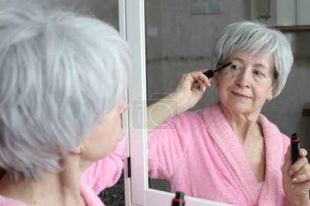 Foto de Primer plano retrato de la mujer madura haciendo maquillaje delante del espejo en el baño - Imagen libre de derechos