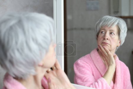 Foto de Primer plano retrato de la mujer madura delante del espejo en el baño - Imagen libre de derechos