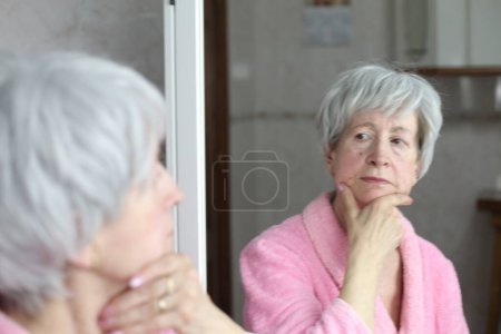 Foto de Primer plano retrato de la mujer madura delante del espejo en el baño - Imagen libre de derechos