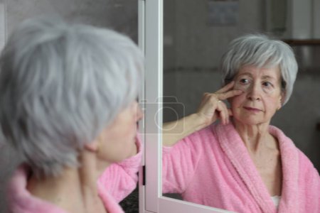 Photo for Close-up portrait of mature woman in front of mirror in bathroom - Royalty Free Image