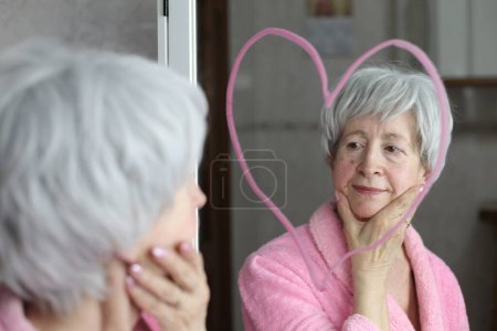 Foto de Primer plano retrato de mujer madura delante del espejo en el baño con dibujo en forma de corazón - Imagen libre de derechos