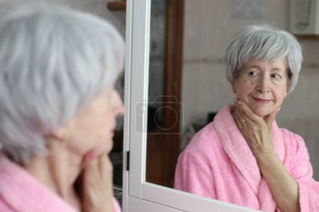 Téléchargez les photos : Portrait en gros plan de femme mature devant le miroir dans la salle de bain - en image libre de droit