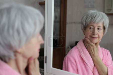 Photo for Close-up portrait of mature woman in front of mirror in bathroom - Royalty Free Image