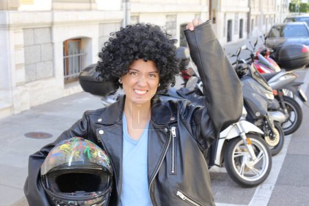 Téléchargez les photos : Portrait de belle jeune femme en veste en cuir avec des cheveux bouclés devant des vélos garés sur la rue de la ville - en image libre de droit