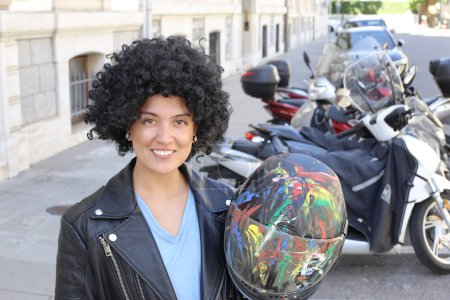 Téléchargez les photos : Portrait de belle jeune femme en veste en cuir avec des cheveux bouclés devant des vélos garés sur la rue de la ville - en image libre de droit