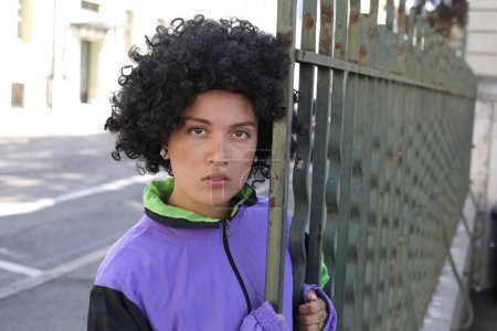 Téléchargez les photos : Portrait de belle jeune femme dans des vêtements élégants avec des cheveux bouclés sur la rue de la ville - en image libre de droit
