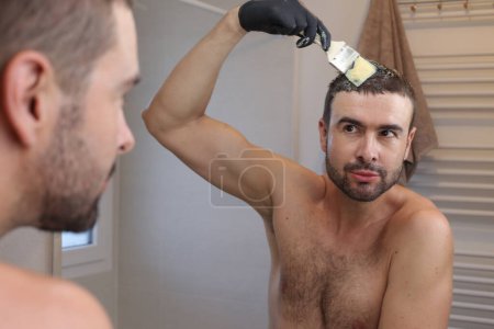 Foto de Retrato del joven pintándose el pelo delante del espejo en el baño - Imagen libre de derechos