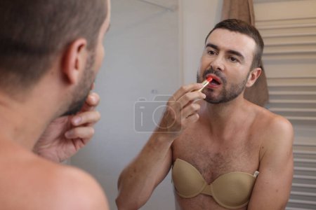 Photo for Portrait of young man with bra in front of mirror in bathroom - Royalty Free Image