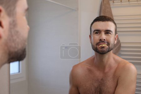 Photo for Portrait of young man in front of mirror in bathroom - Royalty Free Image