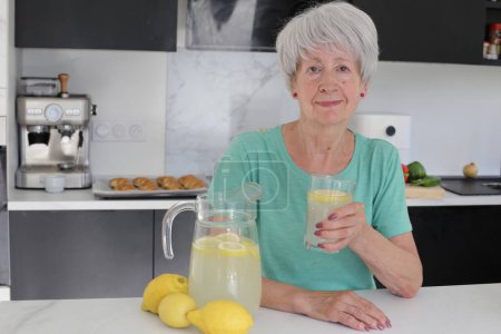 Photo for Close-up portrait of mature woman with jug of lemonade at kitchen - Royalty Free Image