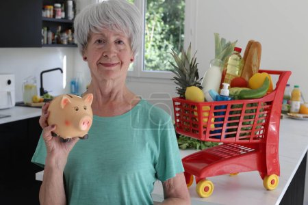 Téléchargez les photos : Portrait en gros plan de femme mature avec panier plein d'épicerie à la cuisine - en image libre de droit