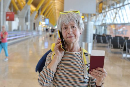 Foto de Primer plano retrato de mujer madura con pasaporte hablando por teléfono en el aeropuerto - Imagen libre de derechos