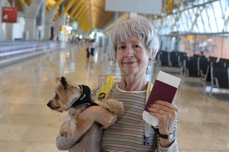 Foto de Primer plano retrato de mujer madura con pasaporte y su adorable perrito en el aeropuerto - Imagen libre de derechos