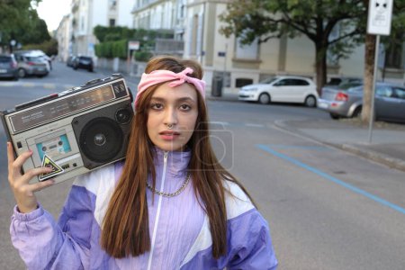 Foto de Elegante mujer hipster con diadema y perforante grabadora de cinta en el fondo urbano - Imagen libre de derechos