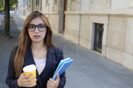 Téléchargez les photos : Jolie femme d'affaires portant des lunettes et costume tenant du café et des documents à l'extérieur - en image libre de droit