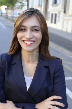 Foto de Mujer de negocios adulta con los brazos cruzados posando al aire libre sonriendo a la cámara con fondo urbano - Imagen libre de derechos