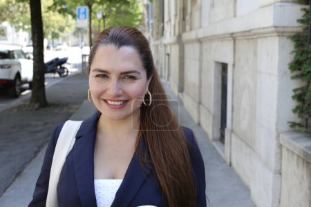 Téléchargez les photos : Portrait de belle jeune femme d'affaires confiante avec tasse de café en papier sur la rue de la ville - en image libre de droit