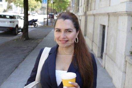 Photo for Portrait of beautiful confident young businesswoman with paper cup of coffee on city street - Royalty Free Image