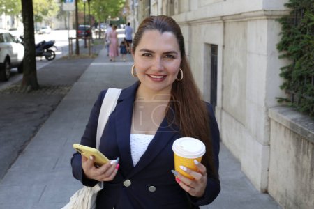 Photo for Portrait of beautiful confident young businesswoman with paper cup of coffee on city street - Royalty Free Image