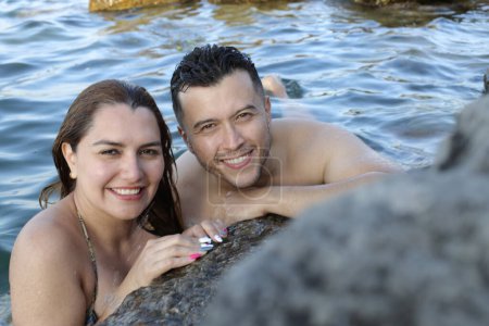 Téléchargez les photos : Portrait en gros plan de jeunes couples posant ensemble dans l'eau au bord de la mer rocheuse - en image libre de droit