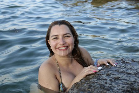 Photo for Close-up portrait of beautiful young woman in bikini posing in water at rocky seashore - Royalty Free Image