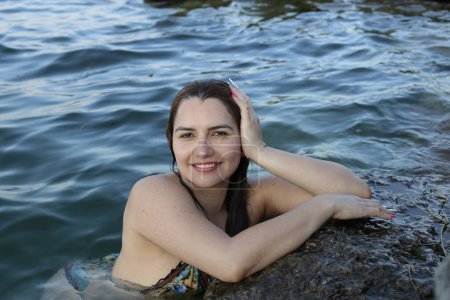 Foto de Retrato de cerca de una hermosa joven en bikini posando en el agua a orillas del mar rocosas - Imagen libre de derechos