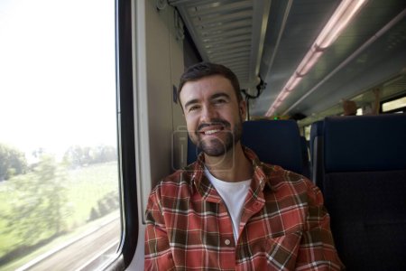 Foto de Retrato de joven feliz guapo viajando en tren - Imagen libre de derechos