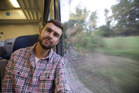 Foto de Retrato de joven feliz guapo viajando en tren - Imagen libre de derechos