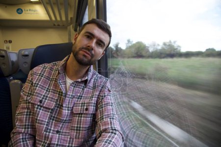 Téléchargez les photos : Portrait d'un beau jeune homme heureux voyageant en train - en image libre de droit