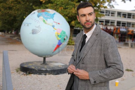 Photo for Portrait of handsome young man with earth globe on background on city street - Royalty Free Image