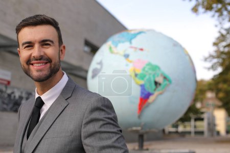 Téléchargez les photos : Portrait de beau jeune homme avec globe terrestre en arrière-plan sur la rue de la ville - en image libre de droit