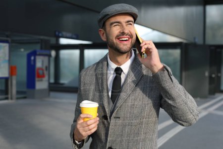 Foto de Retrato de joven guapo en traje gris con taza de papel de café en la calle de la ciudad - Imagen libre de derechos
