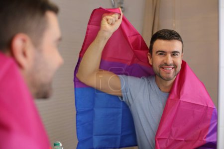 Photo for Portrait of handsome young man with Bisexual Flag in front of mirror in bathroom - Royalty Free Image