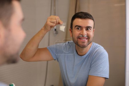 Téléchargez les photos : Portrait de beau jeune homme avec de la drogue en poudre sous le nez devant le miroir dans la salle de bain - en image libre de droit