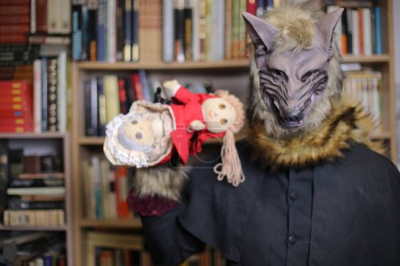 Foto de Primer plano de la persona en la máscara de lobo en casa con el juguete capucha roja - Imagen libre de derechos