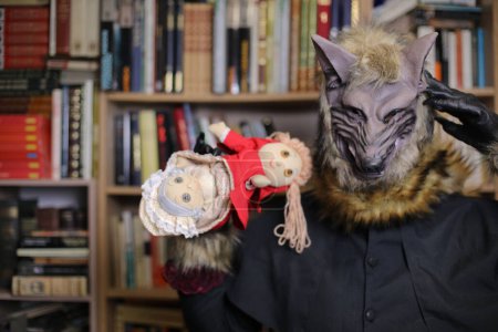 Téléchargez les photos : Gros plan de la personne dans le masque de loup à la maison avec un jouet capuche rouge - en image libre de droit