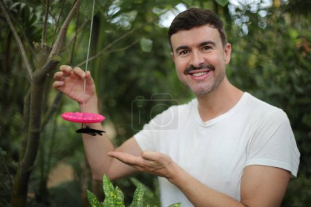 Téléchargez les photos : Portrait d'un beau jeune homme nourrissant un papillon dans une forêt tropicale - en image libre de droit
