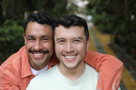 Téléchargez les photos : Jeune couple gay heureux de deux beaux hommes embrassant dans le parc - en image libre de droit