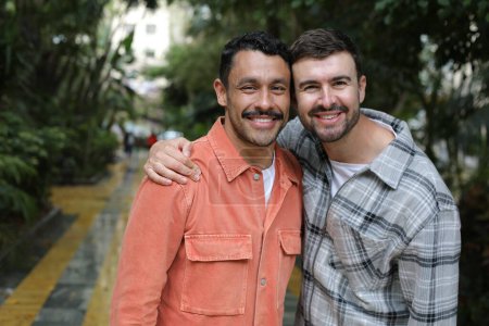 Téléchargez les photos : Jeune heureux gay couple de deux beaux hommes dans vert parc - en image libre de droit