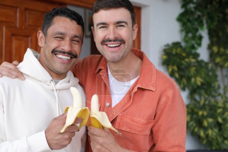 Téléchargez les photos : Jeune heureux gay couple de deux beaux hommes avec bananes - en image libre de droit