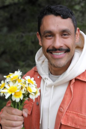 Foto de Retrato del guapo hombre hispano con bigote sosteniendo ramo de manzanillas - Imagen libre de derechos